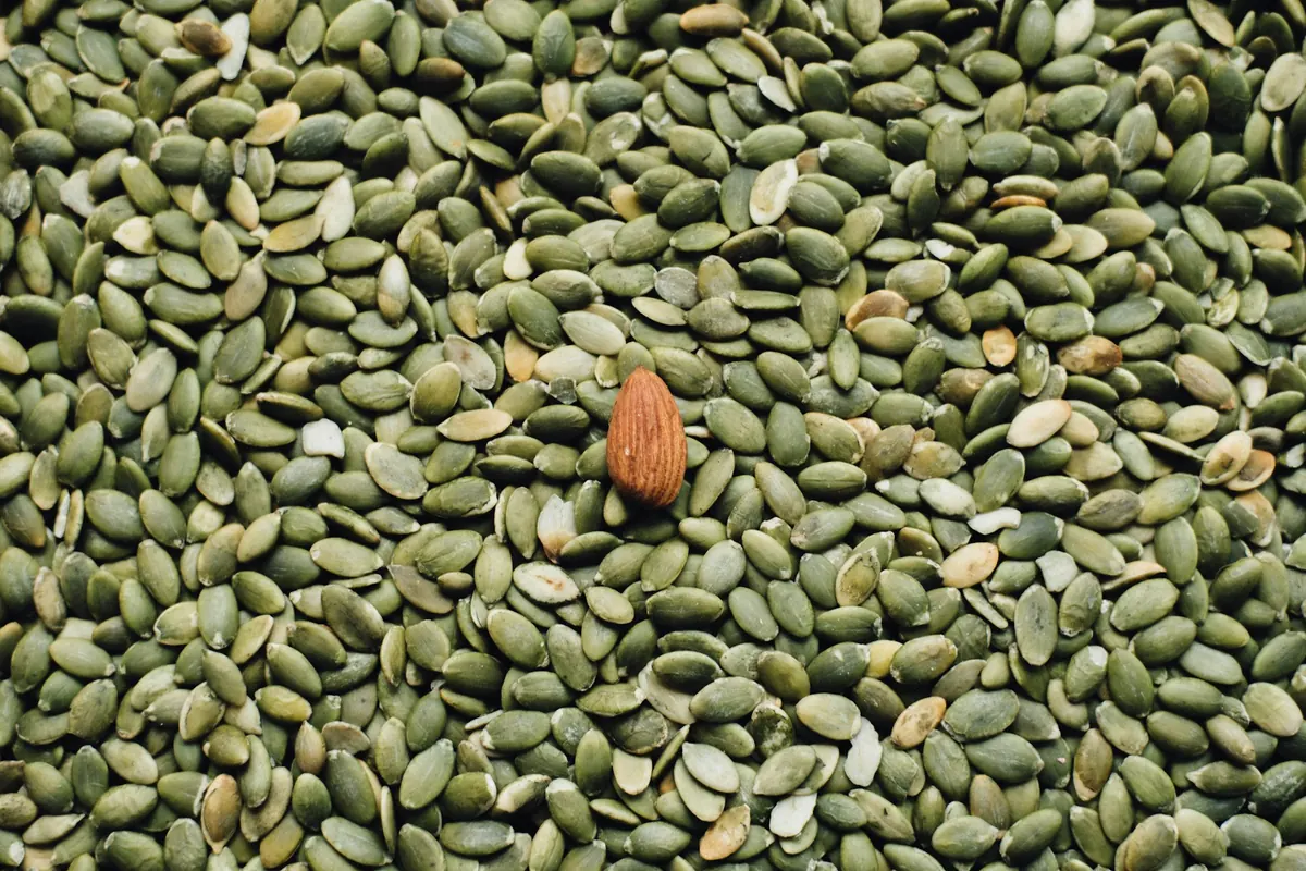Close-up of green pumpkin seeds with a single almond