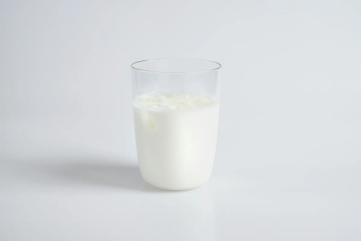 A clear glass of milk on a pale grey background