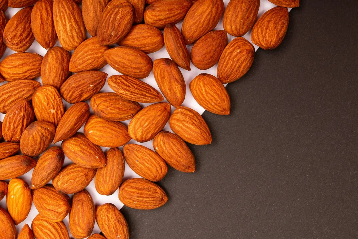 Roasted almonds piled on a white and charcoal background